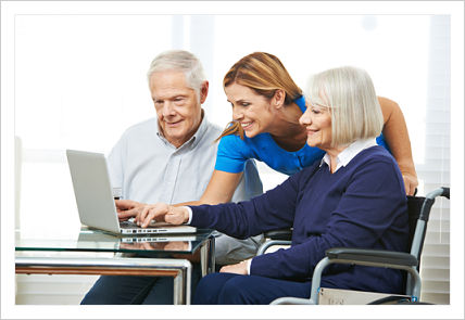 A female nurse is assisting and elderly man and women with filling information on the computer