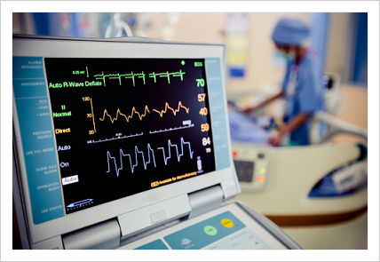 An image of a hospital heart rate monitor and a nurse in the background.